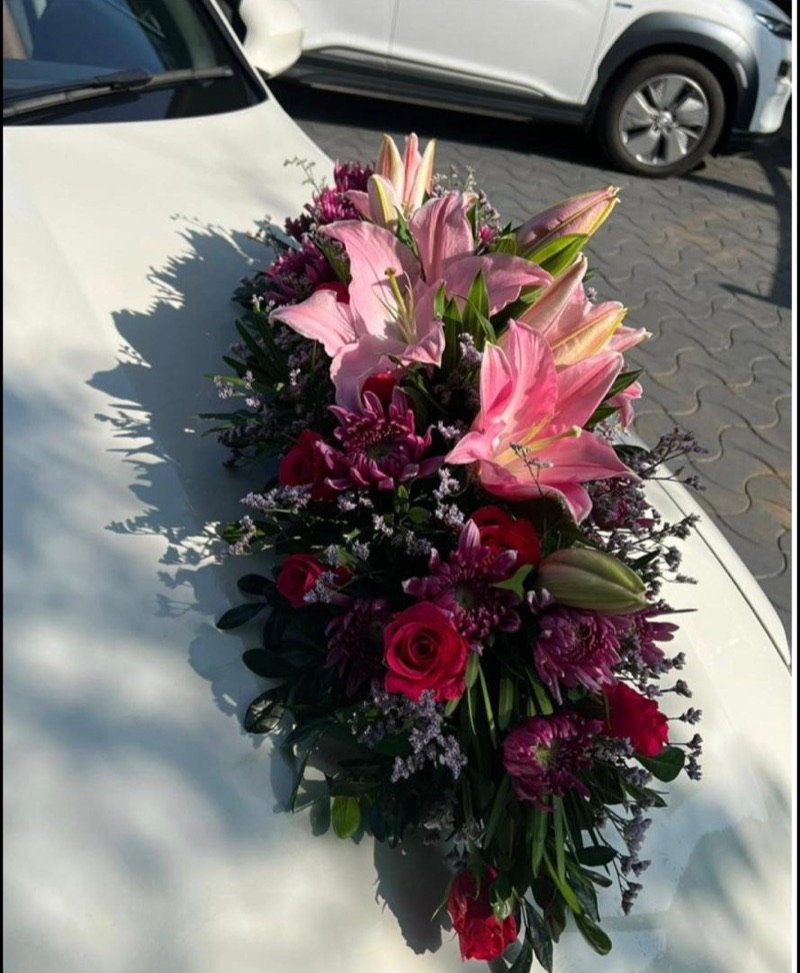 Pink lilies and roses on a white wedding car bonnet